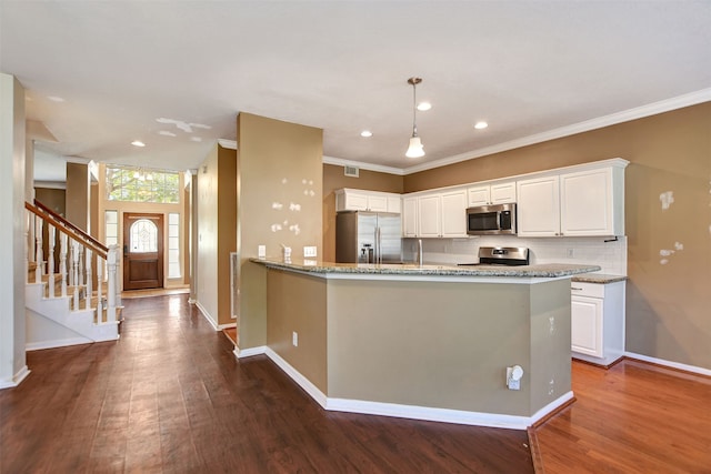 kitchen with light stone counters, ornamental molding, stainless steel appliances, hardwood / wood-style floors, and white cabinetry