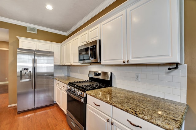 kitchen featuring backsplash, stone counters, appliances with stainless steel finishes, light hardwood / wood-style floors, and white cabinetry