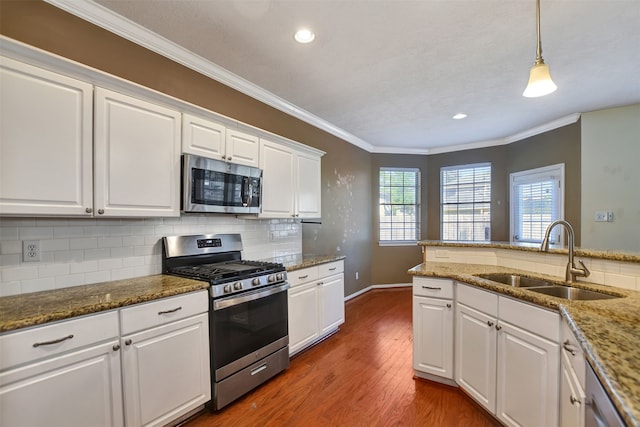 kitchen with sink, dark wood-type flooring, pendant lighting, white cabinets, and appliances with stainless steel finishes