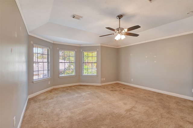 carpeted empty room with ceiling fan, a healthy amount of sunlight, crown molding, and a tray ceiling