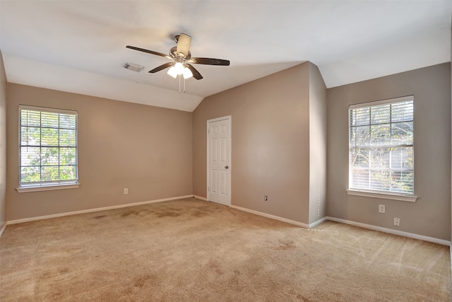 spare room featuring light carpet, a healthy amount of sunlight, and vaulted ceiling