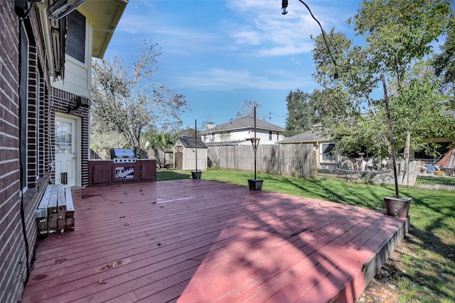 wooden terrace with a grill, a shed, and a yard