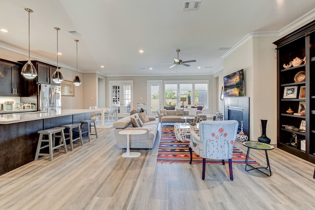 living room featuring ceiling fan, light hardwood / wood-style floors, and crown molding