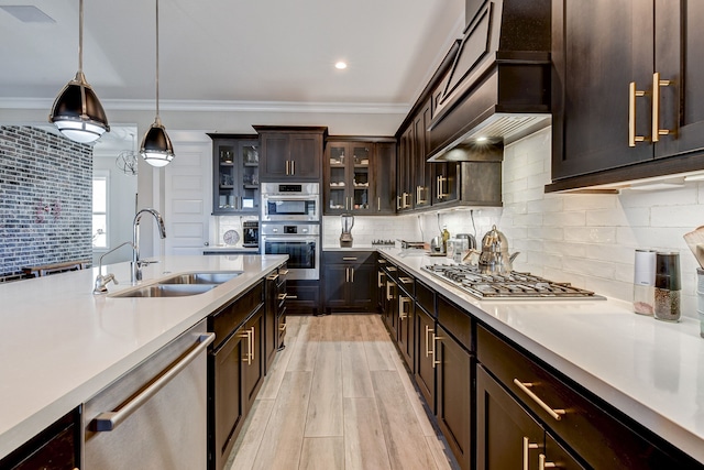 kitchen with pendant lighting, backsplash, sink, appliances with stainless steel finishes, and dark brown cabinetry