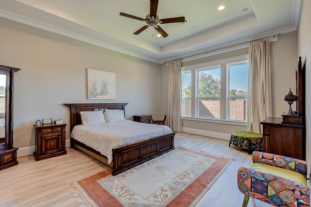 bedroom featuring ceiling fan, light hardwood / wood-style floors, a tray ceiling, and multiple windows