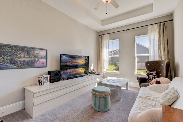 carpeted living room featuring a tray ceiling and ceiling fan