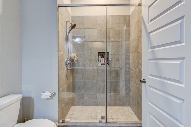 bathroom with a shower with shower door and toilet