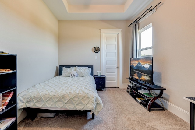 carpeted bedroom featuring a raised ceiling