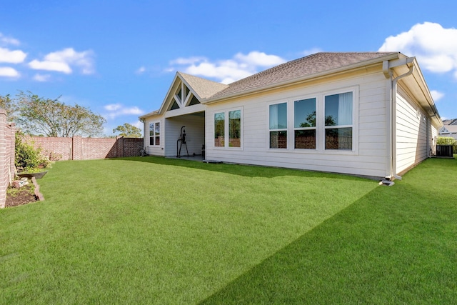 rear view of house featuring central air condition unit and a lawn