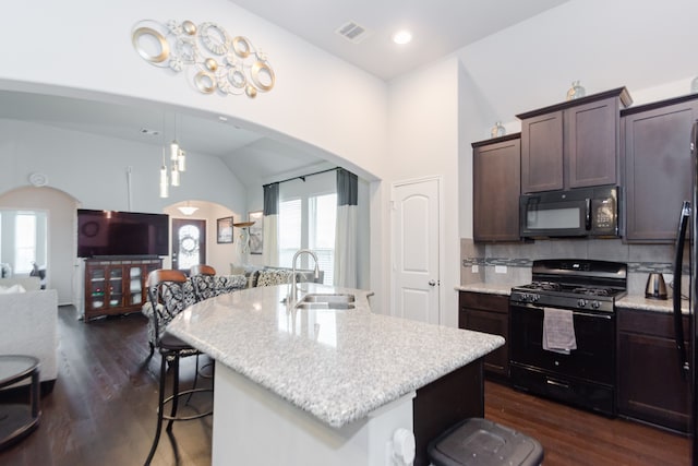 kitchen with black appliances, a center island with sink, sink, vaulted ceiling, and dark hardwood / wood-style floors