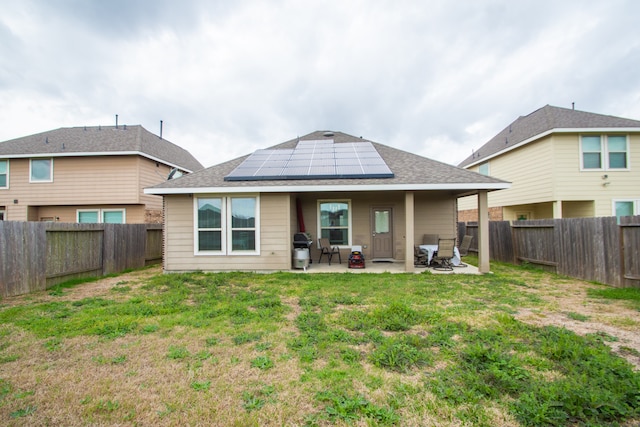 rear view of house with a lawn, solar panels, and a patio