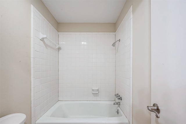 bathroom featuring tiled shower / bath combo and toilet