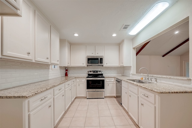 kitchen featuring sink, kitchen peninsula, light stone countertops, white cabinetry, and stainless steel appliances