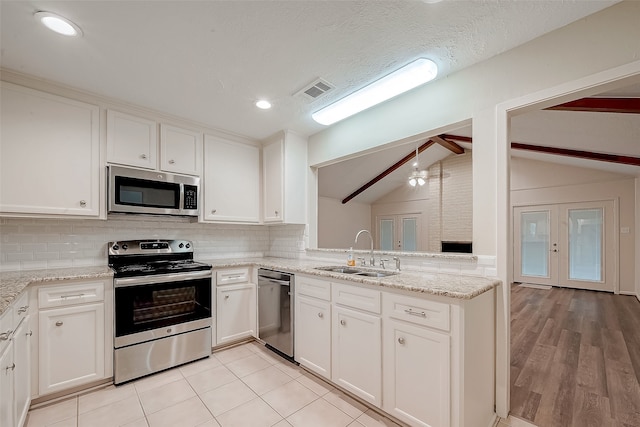 kitchen featuring sink, white cabinets, lofted ceiling with beams, and appliances with stainless steel finishes