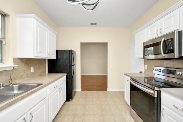 kitchen featuring backsplash, white cabinetry, sink, and appliances with stainless steel finishes