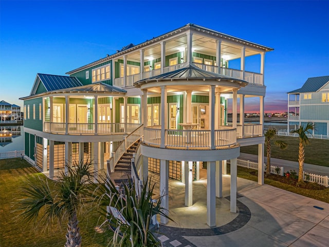 back house at dusk featuring a balcony and a carport