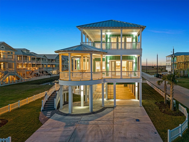 back house at dusk featuring a carport and a balcony