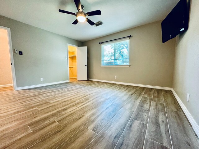 unfurnished bedroom with ceiling fan, a spacious closet, and a closet