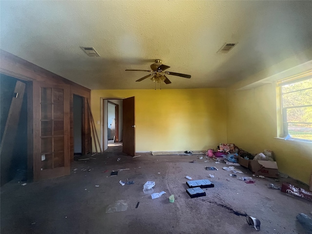 interior space featuring dark colored carpet, ceiling fan, and a textured ceiling