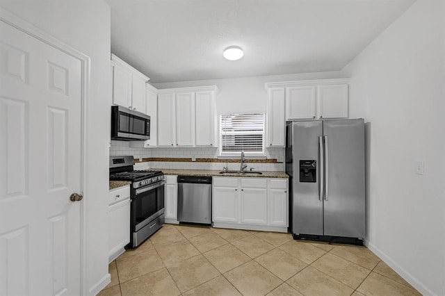 kitchen featuring backsplash, dark stone counters, white cabinets, sink, and stainless steel appliances