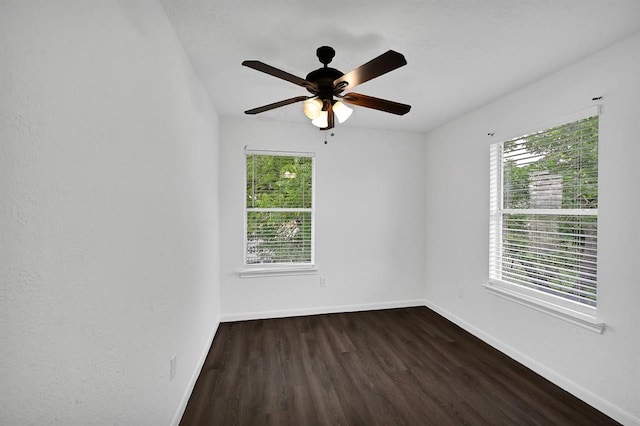 spare room featuring a wealth of natural light, ceiling fan, and dark hardwood / wood-style floors