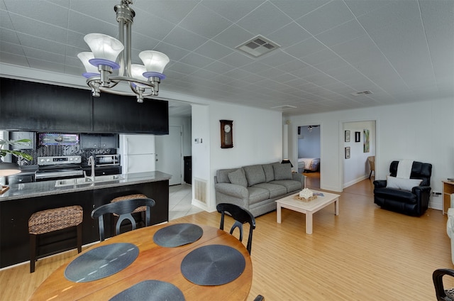 dining room with sink, light hardwood / wood-style floors, and a notable chandelier