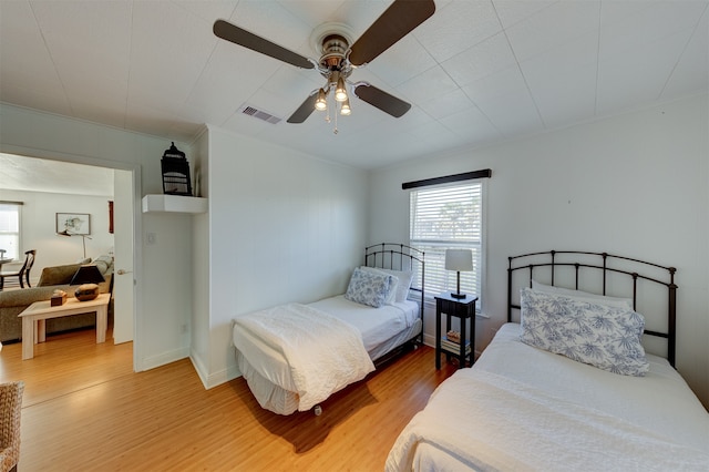 bedroom featuring multiple windows, hardwood / wood-style flooring, and ceiling fan