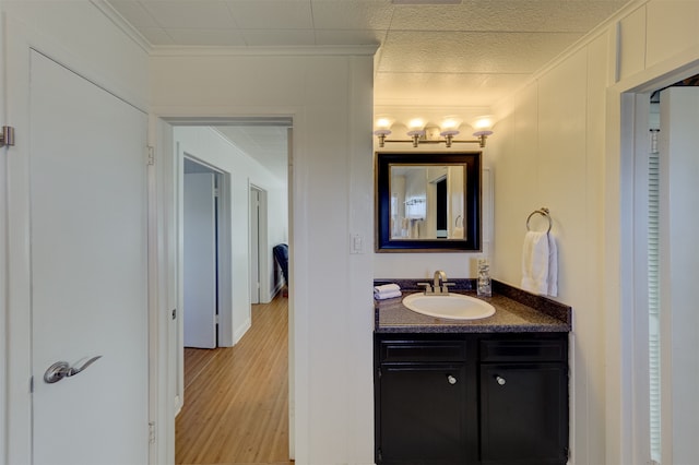 bathroom featuring crown molding, vanity, and wood-type flooring