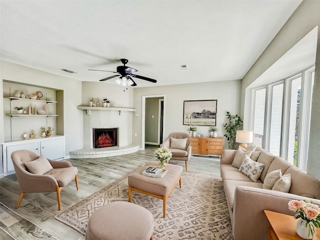 living room with ceiling fan, light wood-type flooring, and a fireplace