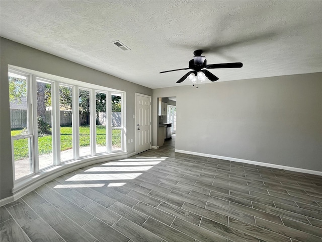 empty room featuring a textured ceiling, dark hardwood / wood-style floors, and a wealth of natural light