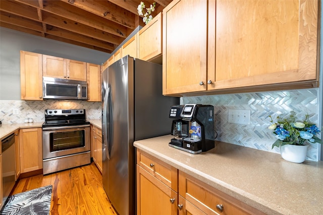 kitchen with light brown cabinets, stainless steel appliances, tasteful backsplash, and light hardwood / wood-style floors