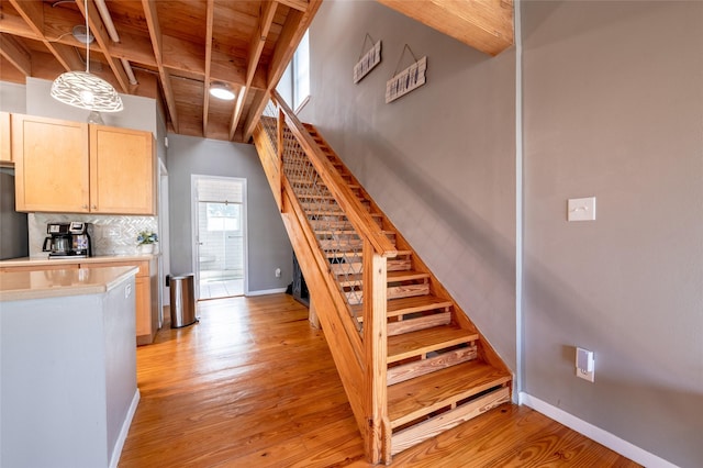 staircase with lofted ceiling with beams, hardwood / wood-style flooring, and wooden ceiling