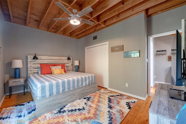 bedroom featuring light hardwood / wood-style flooring, ceiling fan, beamed ceiling, wood ceiling, and a closet