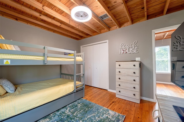 bedroom featuring beamed ceiling, light hardwood / wood-style floors, a closet, and wood ceiling