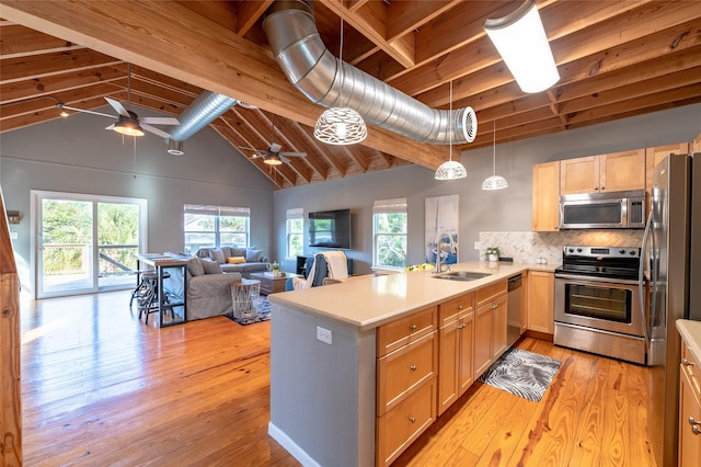 kitchen with kitchen peninsula, appliances with stainless steel finishes, ceiling fan, sink, and beam ceiling