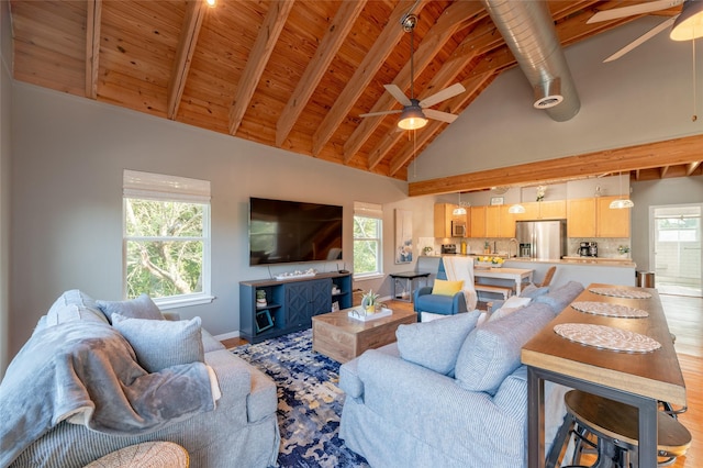 living room with beam ceiling, light wood-type flooring, high vaulted ceiling, and a healthy amount of sunlight