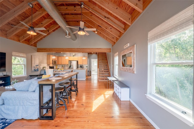 living room with beam ceiling, light wood-type flooring, high vaulted ceiling, and wood ceiling