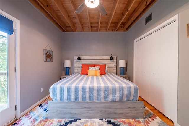 bedroom featuring ceiling fan, beamed ceiling, light hardwood / wood-style floors, wood ceiling, and a closet