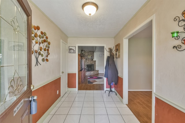 hallway with crown molding, light hardwood / wood-style floors, and a textured ceiling