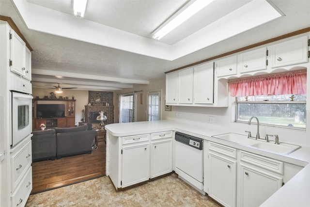 kitchen with white appliances, sink, kitchen peninsula, light hardwood / wood-style flooring, and white cabinetry