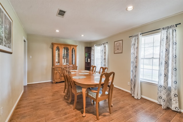 dining area featuring plenty of natural light, light wood-type flooring, and ornamental molding