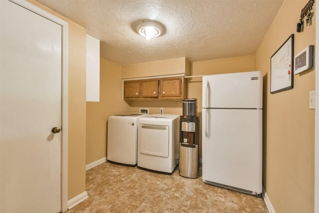 clothes washing area featuring cabinets, a textured ceiling, and washing machine and clothes dryer