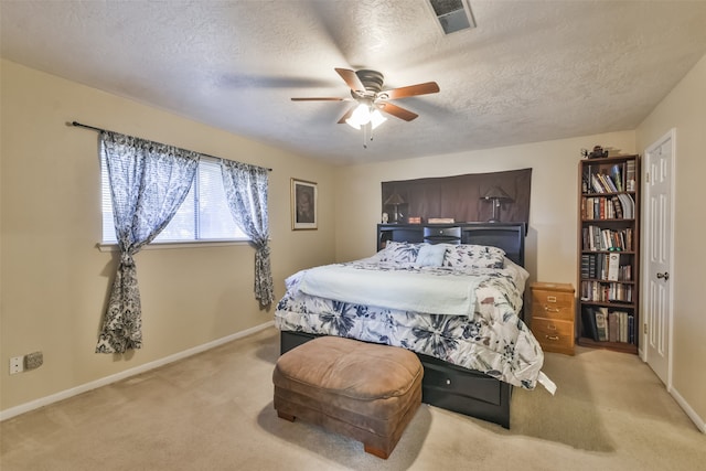 bedroom with ceiling fan, light colored carpet, and a textured ceiling