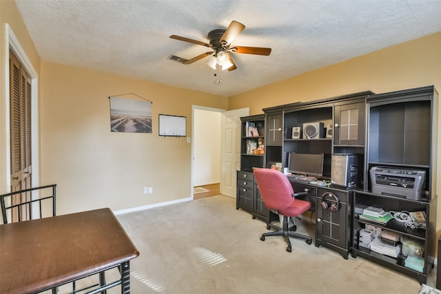 office with a textured ceiling, ceiling fan, and light carpet