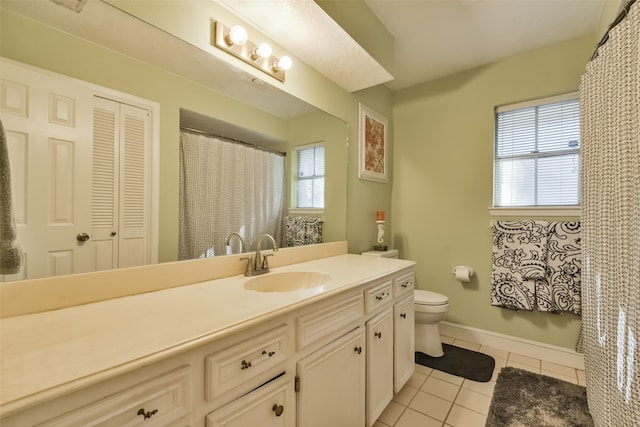 bathroom with tile patterned floors, plenty of natural light, toilet, and vanity