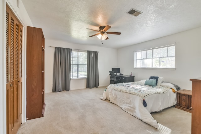 carpeted bedroom featuring a textured ceiling, a closet, and ceiling fan