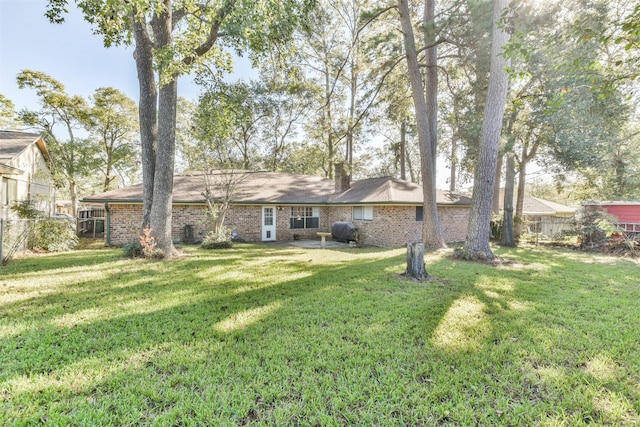 rear view of property with brick siding, a yard, and fence