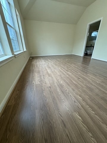 empty room with dark wood-type flooring and lofted ceiling