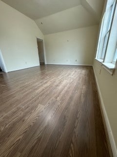 unfurnished room with dark hardwood / wood-style flooring and vaulted ceiling