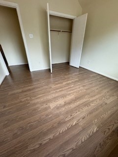 unfurnished bedroom featuring a closet and dark wood-type flooring